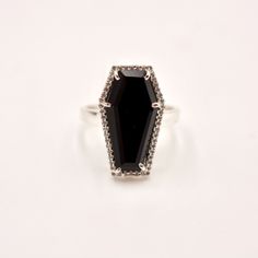 Make a striking impression with our Statement Coffin Ring, showcasing a coffin-shaped Black Onyx set in sterling silver. This distinctive piece combines the protective qualities of Black Onyx with a bold, gothic aesthetic. Key Benefits & Features: Exquisite Materials: Crafted with a pave crystal bezel-set Black Obsidian and sterling silver, this ring is both durable and visually striking. Distinctive Design: The coffin shape lends a bold and unique touch, perfect for those who embrace a daring s Coffin Ring, Obsidian Ring, Gemstone Properties, Coffin Shape, Gothic Aesthetic, Back Jewelry, Demi Fine Jewelry, Black Obsidian, Fine Jewellery Necklace