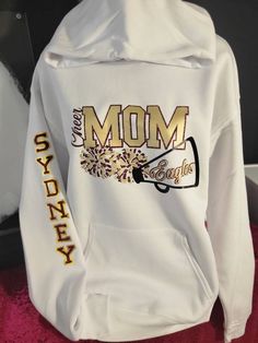 The Cheer Mom hoodie is custom made with colors that best represent your athlete's team. The design cost includes two colors. Personalization is offered (additional fees apply, see the options available for more details). If you have any questions, please don't hesitate to contact us. *Colors may vary but we will do our best to match the team colors as best as possible. A photo really helps. Cheer Mom Hoodie Ideas, Cheer Mom Sweatshirt, Cheer Team Gifts For Competition, Cheer Mom Outfit Ideas, Cheer Mom Sweatshirt Ideas, Senior Cheer Mom Shirts, Cheer Sweatshirts Design, Cheer Mom Outfit, Cheer Tshirt Designs