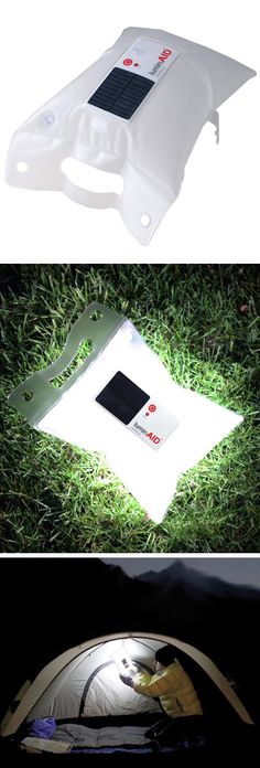 a solar panel laying on the grass next to a cell phone charger and bag