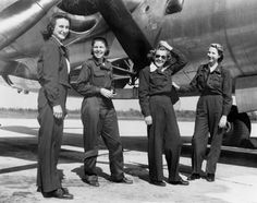 four women standing in front of an airplane