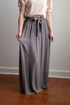 Breathing timeless charm, the Kristin pull-on style skirt features a comfortable elastic waistband with an attached tie belt at the waist front. It falls to the ankle in graceful gathers. Complete the feminine look with an elegant blouse. Fit: true to size Style: gathered dress skirt with elastic waistband and attached tie at the waist Color: charcoal Fabric content: 100% rayon Care instructions: wash gentle cycle, cold; lay flat to dry, cool iron if needed. For best results, always follow care instructions on garment label. Our sizing is always approximate and can vary due to personal preference and style. For the best experience - and to make life easier for everyone! - please carefully measure yourself before placing your order and allow 1" variance due to product manufacturing. If you Product Manufacturing, Skirt With Elastic Waistband, Be Intentional, Gathered Dress, Modest Clothing, Elegant Blouses, Garment Labels, Style Skirt, Curated Gifts