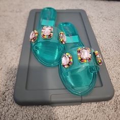 Add A Pop Of Glam To Your Shoe Collection With These Betsey Johnson Women's Madilyn Jelly Sandals. The Black Jelly Sandals Are Adorned With Glitter, Beaded, And Rhinestone Accents, Making Them Perfect For A Night Out Or Any Occasion That Calls For Some Sparkle. These Flat Sandals Feature A Pvc Upper Material And A Slide Style For Easy Wear. The Madilyn Model Comes In Size 6 And Is Brand New In Box. Whether You're Pairing Them With A Casual Outfit Or Dressing Up, These Sandals Are Sure To Add Som Closed Toe Turquoise Sandals For Summer, Turquoise Closed Toe Sandals For Summer, Turquoise Synthetic Sandals For Spring, Blue Slip-on Jelly Sandals For Summer, Blue Adjustable Jelly Sandals With Round Toe, Blue Jelly Sandals With Round Toe For Party, Blue Flat Jelly Sandals For Summer, Turquoise Synthetic Sandals With Round Toe, Turquoise Round Toe Synthetic Sandals