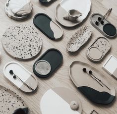 many different plates and spoons are arranged on the table top, with black and white designs