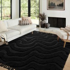 a living room with black rugs and white couches in front of large windows