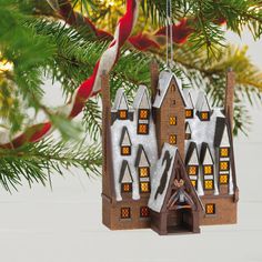 a christmas ornament hanging from a tree with snow covered buildings in the background