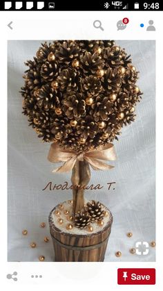 a small pine cone tree in a pot with gold balls on it's sides