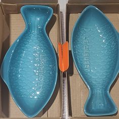 two large blue vases sitting in a box next to an orange handled spoon and fork