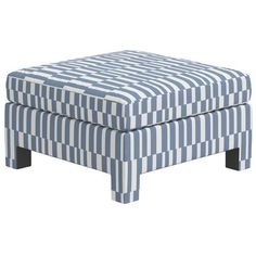 a blue and white striped ottoman sitting on top of a wooden table