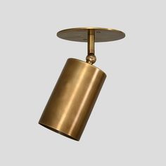 a brass colored light fixture on a gray background with an overhead view of the lamp