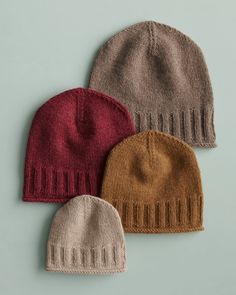 three knitted hats sitting on top of each other, one brown and one red