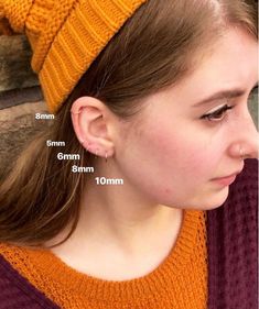 a girl wearing an orange knitted beanie hat and earring size guide on her head