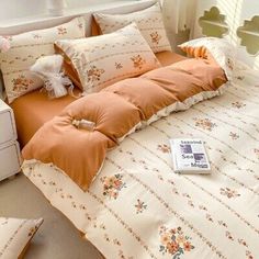 a bed with an orange comforter and pillows