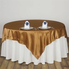 a table with two plates on it that are covered in gold and white cloths