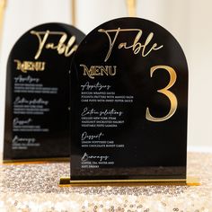 two black and gold table numbers on top of each other