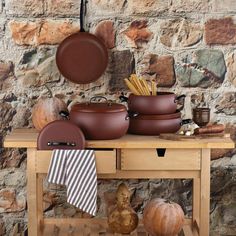 pots and pans are sitting on a table next to an old brick wall,