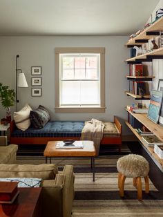 a living room filled with lots of furniture and bookshelves next to a window