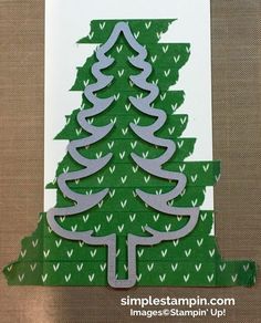 a christmas tree cut out of paper on top of a piece of cardboard with scissors