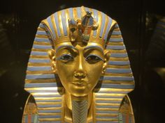 an egyptian statue with gold and blue stripes on it's head, in front of a black background