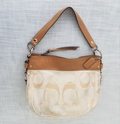 "Vintage COACH Zoe ivory / beige /cream shoulder bag with C monogram.  Tan leather trim.  One zippered and two slip pockets inside.  Zippered top closure.  Leather embossed COACH hangtag. Coach Patched Creed:  \"COACH - This is a COACH Bag . It Was Handcrafted in China From The Finest Materials and Leather.  It's Superior Craftsmanship Reflects Our Enduring Quality - No C1082-F14711\" Size: 13\" (L) x 10\" (H) x 4\" (W), 8\" drop  Vintage Condition:  Good vintage condition with light general wea White Leather Trim Crossbody Shoulder Bag, Cream Leather Shoulder Bag With Leather Trim, Cream Shoulder Bag With Leather Trim, Chic Cream Shoulder Bag With Leather Trim, Cream Crossbody Bag With Leather Trim, Cream Leather Trim Crossbody Bag, Cream Satchel Bag With Leather Trim, Classic Beige Shoulder Bag With Zipper Closure, Classic White Shoulder Bag With Leather Trim