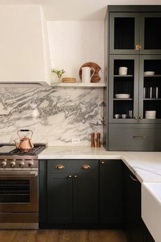 a kitchen with marble counter tops and black cabinets, along with an open shelving unit