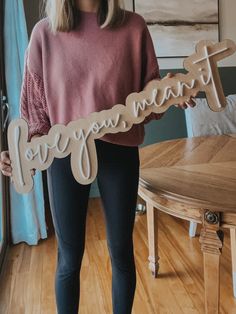 a woman standing in front of a table holding a wooden sign that says, be you mama