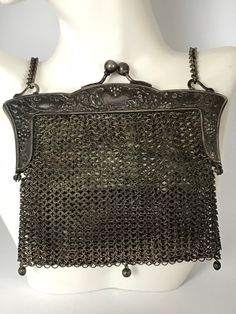 "This sweet little silver chain mail bag is truly a collector's gem. Hand crafted chainmail mesh body attached to a 2 piece hinged kiss-lock closure frame all crafted in German Silver. Beautiful but simple floral pattern on the frame. Lined in white kidglove leather, this lining is worn and soiled. Bag is otherwise in great condition. Measures approx. 5\" x 4.5\". Chain has a 7\" drop." Silver Chainmail Bag For Everyday Use, Silver Metal Rectangular Bag, Elegant Silver Bag With Chainmail Detail, Silver Metal Chain Link Bag, Elegant Silver Chainmail Bag, Silver Metal Chainmail Bag, Elegant Silver Chain Link Bag, Silver Chainmail Evening Bag, Silver Chain Bag For Wedding