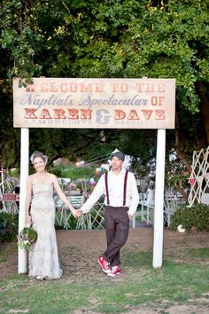 a man and woman holding hands in front of a sign