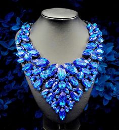 "Blue Paradise": Dare to step into the unknown and explore the depths of fashion and style with the Blue Paradise Necklace. This bold statement necklace will spice up any outfit and help you stand out with its vibrant blue color. Take the plunge and make a statement with this amazing accessory! Blue stone bib has multiple hinges which allows this necklace to move with the body. Approximately 21" with extender. Blue stone adorned bib measures about 7" long! Elegant Blue Crystal Necklaces For Parties, Royal Blue Crystal Jewelry For Party, Party Turquoise Crystal Necklaces, Blue Crystal Necklaces For Party, Elegant Blue Crystal Necklace For Party, Blue Crystal Necklace For Party, Blue Crystal Party Necklace, Blue Choker Jewelry For Party, Blue Crystal Rhinestone Necklace For Party