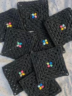 six black crocheted coasters with multicolored candies on them