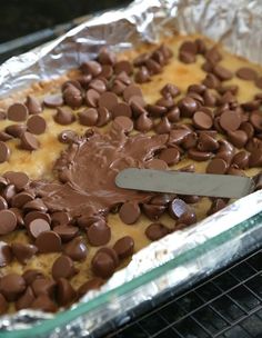 chocolate chips are spread over the top of a baked dessert in an aluminum baking pan