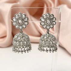 "These silver-plated polki jhumka earrings are a stunning addition to any outfit. The intricate detailing and beautiful silver beaded accents add an elegant touch to this Bollywood inspired piece, while polki stones give it a gorgeous sparkle that's sure to catch light and make heads turn. Length 1.7\" | Width 1\" Items are carefully packed and ready for gifting. All pictures are taken in natural light please allow for slight variations in color due to camera settings. Jewelry Care ✨Protect your Silver Bridal Earrings For Festive Occasions, Silver Bollywood Jhumkas With Matching Earrings, Silver Bollywood Bridal Earrings With Latkans, Silver Bridal Earrings With Latkans For Eid, Silver Chandbali Bridal Earrings For Eid, Silver Bollywood Style Drop Jhumkas, Silver Jhumkas For Wedding, Silver Bollywood Chandelier Earrings For Festive Occasions, Elegant Silver Jhumkas For Eid