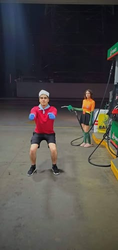 two people are doing exercises in front of a gas station pumper with their arms stretched out