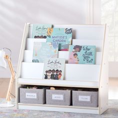 a white book shelf with books on it and two bins under the shelves that hold children's books