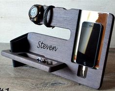 a cell phone and watch on a wooden stand with the name steven written on it