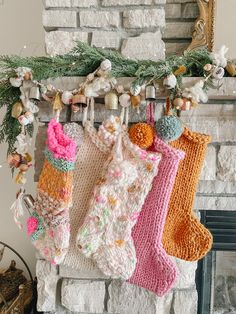 three knit stockings hanging from a mantel over a fireplace with christmas decorations on it