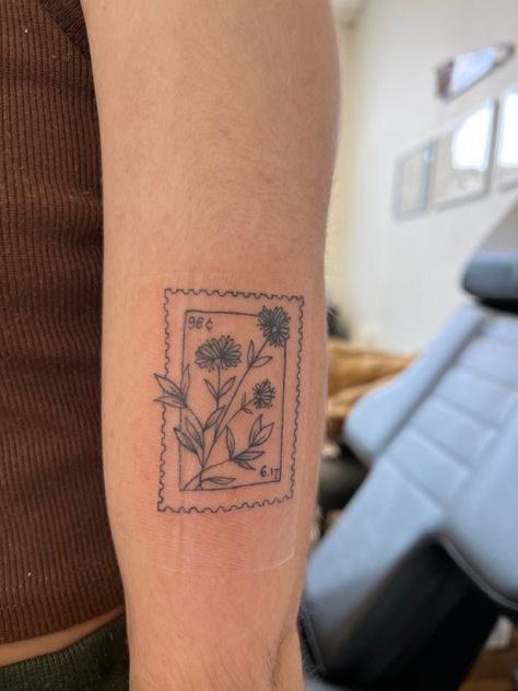 Photo of a tattoo that is inspired by a postage stamp. Flower Stamp Tattoo Ideas, Folky Flower Tattoo, Small Stamp Tattoo Ideas, Peony Stamp Tattoo, Wildflower Stamp Tattoo, Flowers In Box Tattoo, Flower Polaroid Tattoo, Honeysuckle Stamp Tattoo, Hollyhocks Flowers Tattoo