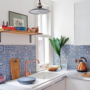 The owners decided to perk up the space by switching out the grey tiles for a rich blue decorative design. They also installed a copper tap, and chose warm-coloured accent throughout, to being a welcoming glow to the kitchen. Blue And White Spanish Kitchen, Talavera Interior Design, Talavera Backsplash Kitchen, Mexican Bungalow, Talavera Kitchen Decor, Talavera Tile Kitchen, Talavera House, Mexican Tile Kitchen, Talavera Kitchen