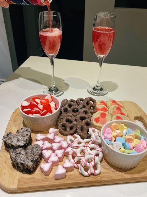 pink/red sparkling cocktails and dessert/snack charcuterie board with valentine’s pillsbury cookies, message heart candies, oreo marshmallow squares, red and white candies, milk and white chocolate covered pretzels. cute valentine’s day date at home. aesthetic food picture. delicious, yummy. Galentines Party Aesthetic Pictures, Valentines Day Food Board, Valentines Day Date Aesthetic, Valentines Candy Aesthetic, Valentines Candy Salad, Candy Board Valentines Day, Date At Home Aesthetic, Valentine’s Day Sleepover, At Home Valentines Date