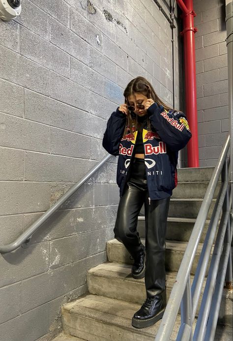 a girl walking down stairs wearing a racing jacket and leather pants Racer Jacket Mini Skirt Outfit, Trendy Fits Summer, Racing Jacket Women Outfit, F1 Jacket Outfit For Women, Motor Cross Jacket Outfit, F1 Race Day Outfit For Women, Street Racing Aesthetic Outfit, Redbull Jacket Aesthetic, Racing Jacket Outfit Women