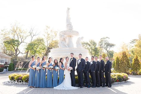 Bridesmaids wear David's Bridal Blue Steel dresses and Groomsmen wearing Black Tuxedos from The Black Tux for a Bridal Party picture in front of a large, white grand fountain at a Surf Club on the Sound Wedding in New Rochelle, NY Steel Blue Bridal Party, Steel Blue Wedding Party, Steel Blue Weddings, Blue Tuxedo Wedding, Steel Blue Bridesmaid Dresses, Black Tuxedos, Slate Blue Wedding, Blue Groomsmen, Light Blue Bridesmaid Dresses