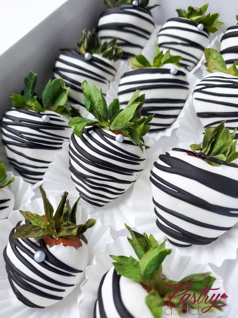 Strawberries dipped in white chocolate, striped with black chocolate and with a silver pearl. Call or email us to design your dream dessert today! #chocolateberries #chocolatecoveredstrawberries #chocolatetreats #desserttables #treattableideas #strawberries #birthdaytreats #dinnerpartyideas Black Dipped Strawberries, Black And White 40th Birthday Decor, Black And White Stripe Decor Party Ideas, Black White And Silver Party Ideas, Black And White Party Foods, White And Silver Strawberries, Black White And Silver Birthday Party, Wednesday Addams Chocolate Covered Strawberries, Black White Dessert Table