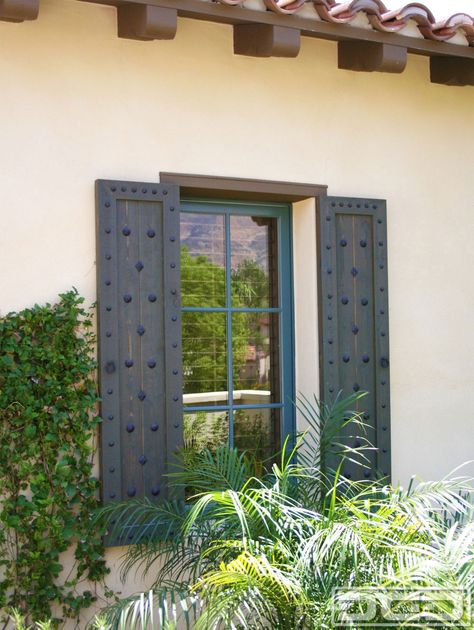 Customized Spanish shutters such as these come in a simple design but the rustic decorative ironwork that is used to embellish these shutters make these shutters a true Spanish architectural accent. Clavos of various sizes as well as diamond head shaped clavos give these shutters their touch of Spanish influence the beautifully stained cedar wood … Spanish Shutters, Mediterranean Shutters, Spanish Style Home Exterior, Exterior Window Shutters, Stained Cedar, Hacienda Homes, Tuscan Style Homes, Exterior Window, House Shutters