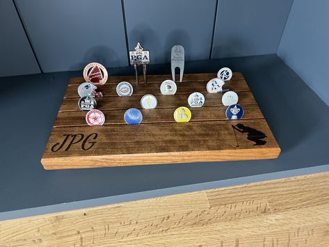 Elevate your golf accessories with our exquisite Cherry Wood Golf Ball Marker Desk Display. This beautifully handcrafted piece, measuring 12'' by 7'', is designed to showcase your favorite coin and poker-sized ball markers in style. Crafted from premium Cherry Wood, this desk display offers a perfect blend of elegance and functionality. The natural wood grain and finish make it a timeless addition to any golf enthusiast's collection. You also have the option to choose a natural or dark oil stain Golf Woodworking Projects, Golf Ball Marker Display, Golf Wood Projects, Ball Marker Display, Golf Display, Desk Display, Golf Score, Oil Stain, Golf Ball Markers