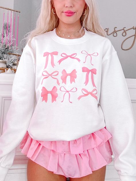 Meet the On Bow Nine Crewneck from Sassy Shortcake! This white sweatshirt is adorned with playful pink bows, bringing a touch of coquette charm to your outfit. She is soft, lightweight, and absolutely adorable! She is paired here with our light pink flirtatious skirt. Unisex crewneck sizing. Model is wearing a size small. Preppy Sweat Shirts, Birthday Outfits Preppy, Cute Preppy Sweatshirts, Coquette Wishlist Ideas, Coquette Outfit Ideas Aesthetic, Flirtatious Skirt, Cute Pink Clothes, Cute Outfits Preppy, Bows Clothes