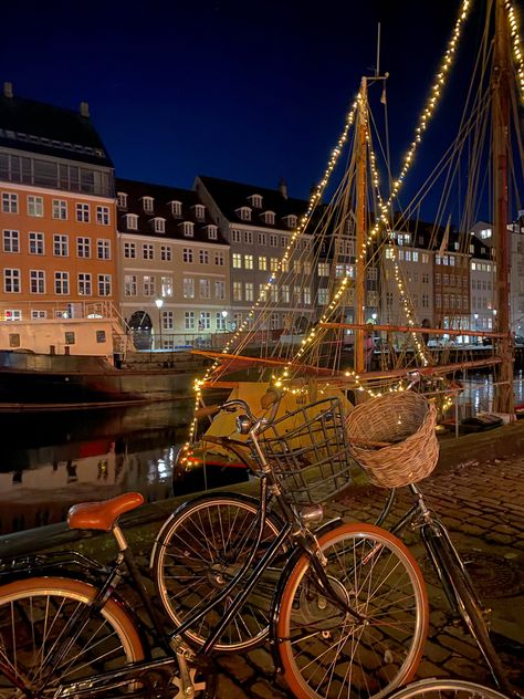 beautiful typical scenery of Copenhagen, pretty color houses in the side of a canal, surrounded by bikes and Christmas lights Fall In Copenhagen, Living In Copenhagen, Copenhagen Fall Aesthetic, Copenhagen At Night, Autumn In Copenhagen, Copenhagen Christmas Aesthetic, Copenhagen Winter Aesthetic, Christmas Copenhagen, Copenhagen Vacation