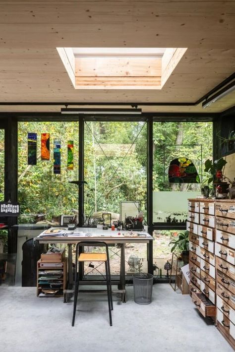 an art studio with a glazed wall, a file cabinet, a metal desk and a stool, some storage units, colorful artwork and potted plants Art Studio In Garden, Garden Art Studio Ideas, Cabin Art Studio, Art Studio In House, Garden Art Studio, Art Studio Architecture, Artist Studio Workspaces, Art Studio Shed, 60s Bungalow