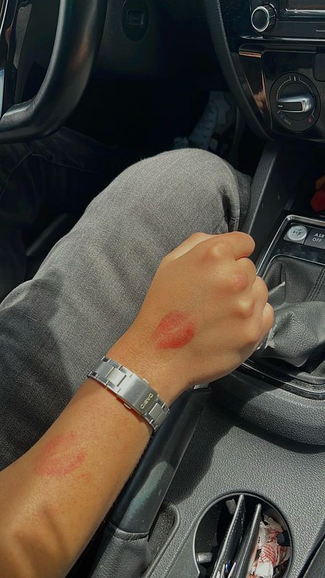 A male arm holding the steering stick of a car is covered with red lipstick kisses. The arm also wears a Casio watch Lipstick Marks On Boyfriend Aesthetic, Secret Couple Picture Ideas, Red Lipstick Kisses Boyfriend, Showing Off Nails Pose With Boyfriend, Lipstick Kisses All Over Face Boyfriend, Couple Lipstick Mark, Secret Photos With Boyfriend, Lipstick On Boyfriend Face, Kiss Marks On Boyfriend