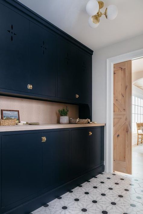 Kitchen features black flat front butlers pantry cabinets with vintage brass latch hardware, gray wash wooden countertops, black and white geometric floor tiles and a reclaimed wood pocket door. Pantry Pocket Door, Dark Blue Cabinets, Floor To Ceiling Storage, Kitchen Island Finishes, Blue Entryway, Transitional Laundry Room, White Pantry, Latches Hardware, Kate Marker Interiors