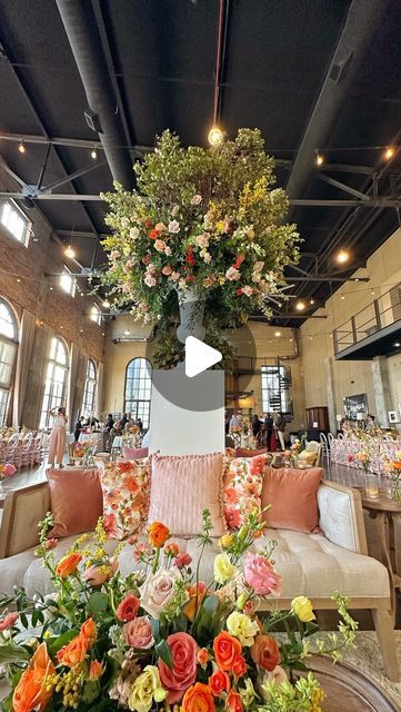 Wedding & Event Florist | Dayton•Cincinnati•OH•KY on Instagram: "It’s a florists dream to be asked, “What would you like to create for this venue without any restrictions?”

Well, we created trees for an industrial space with towering 60 foot ceilings. 

Let’s talk about mechanics…

Height: We used a 12 foot ladder, 6 foot manzanita branches, 4 foot metal vase atop of a 5 foot column. 

Weight: Who knows 😂. The column weighs around 100 lbs, vase 60 lbs, 5 soaked oasis cages 25 lbs, branches, 60 lbs and hundreds of fresh floral stems. 

Style and Color: We were inspired by Reverie Social’s floral print linen, and who wouldn’t be!?! A bright floral pattern of peach, orange, coral and persimmon with accents of sage and gold.  It was a palate of color and texture that truly brought us joy.

A Wall Draping, Clear Chairs, Manzanita Branches, Flower Installation, Industrial Space, Metal Vase, Orange Coral, Peach Orange, Persimmon