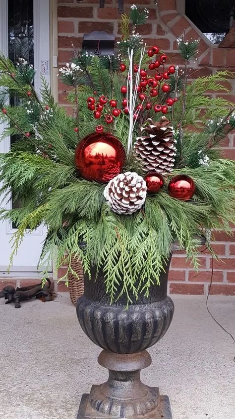 90+ Easy DIY Outdoor Christmas Decorations - Holidappy Front Door Christmas Planters, Outdoor Christmas Urns Planters, Urn Planters Front Door Christmas, Large Ornaments Outside, Holiday Porch Pots, Christmas Flower Pots Outdoor, Christmas Pots Outside Front Porches, Christmas Urns Front Porch, Porch Pots Christmas